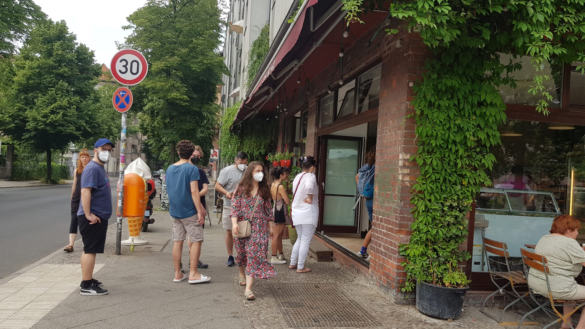 Der efeubewachsene Eingang mit Gästen an der Backsteinfassade