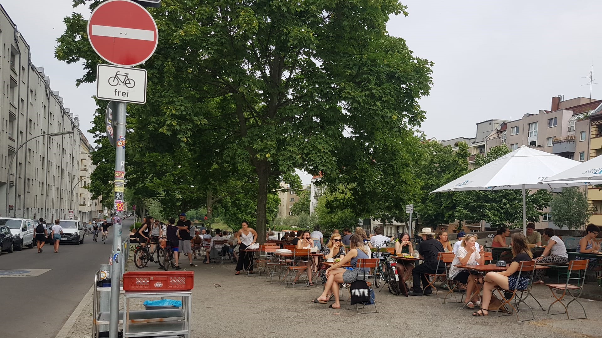 Volle Sommerterrasse unter Bäumen am Weigandufer